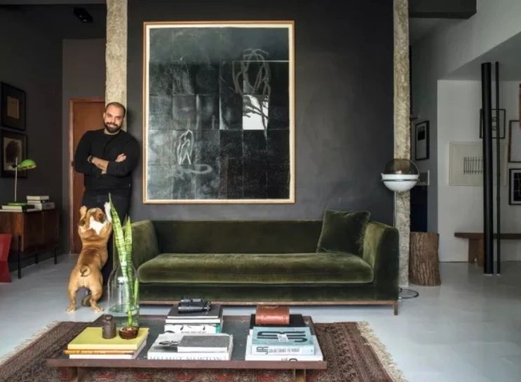 SALA DE ESTAR | Paulo posa com Pina, sua buldogue inglesa, ao lado da parede com tinta acetinada preta da Suvinil. Quadro do artista mineiro Bruno Rios. Sofá ve